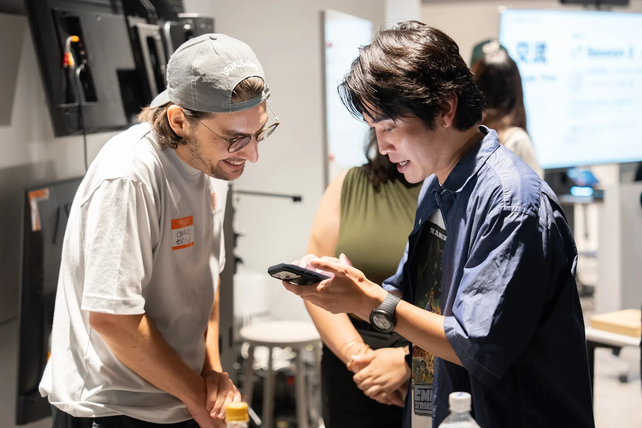 Cédric laughing while looking at a phone with another attendee